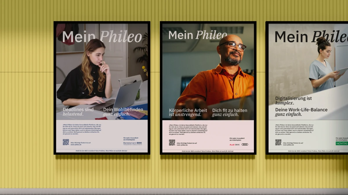 Drei verschiedene Werbeprints von Mein Phileo Markenkampagne in Bilderrahmen an gelber Wand