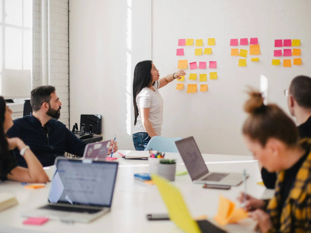 Frau klebt in Meeting Haftnotizen an die Wand