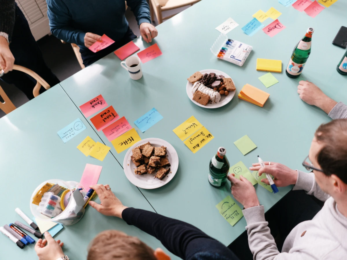 Prozesse digitalisieren: Projektteam sitzt um Tisch mit Klebezetteln und plant Projekt.