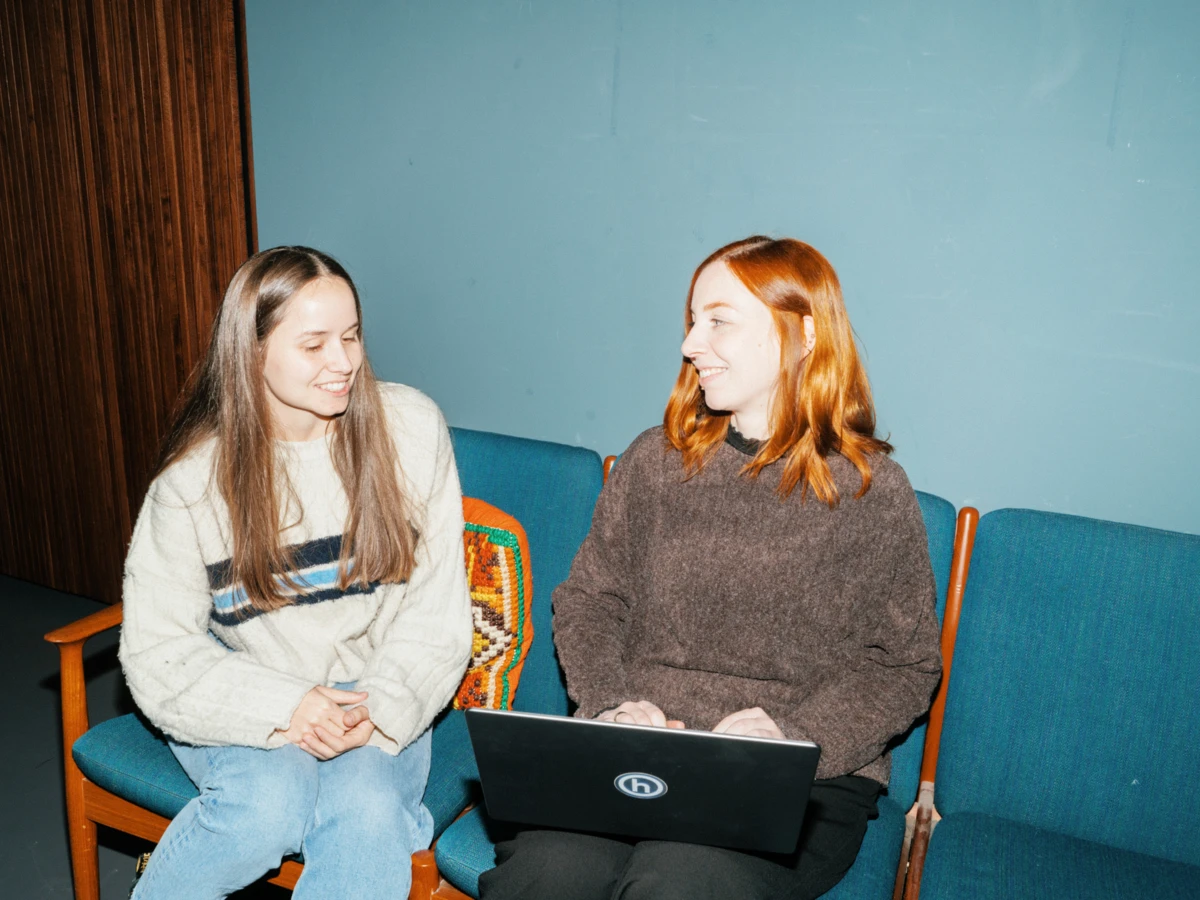 Zwei Mitarbeiterinnen besprechen sich mit Laptop auf Sofa 