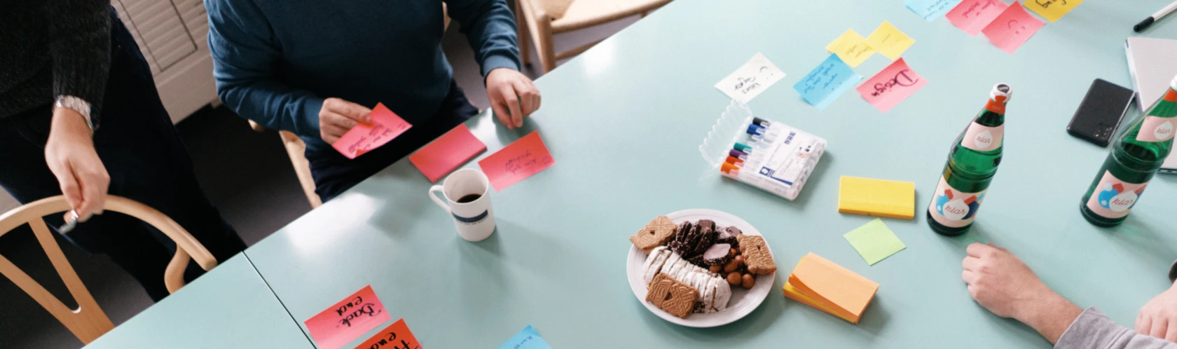 Prozesse digitalisieren: Projektteam sitzt um Tisch mit Klebezetteln und plant Projekt.