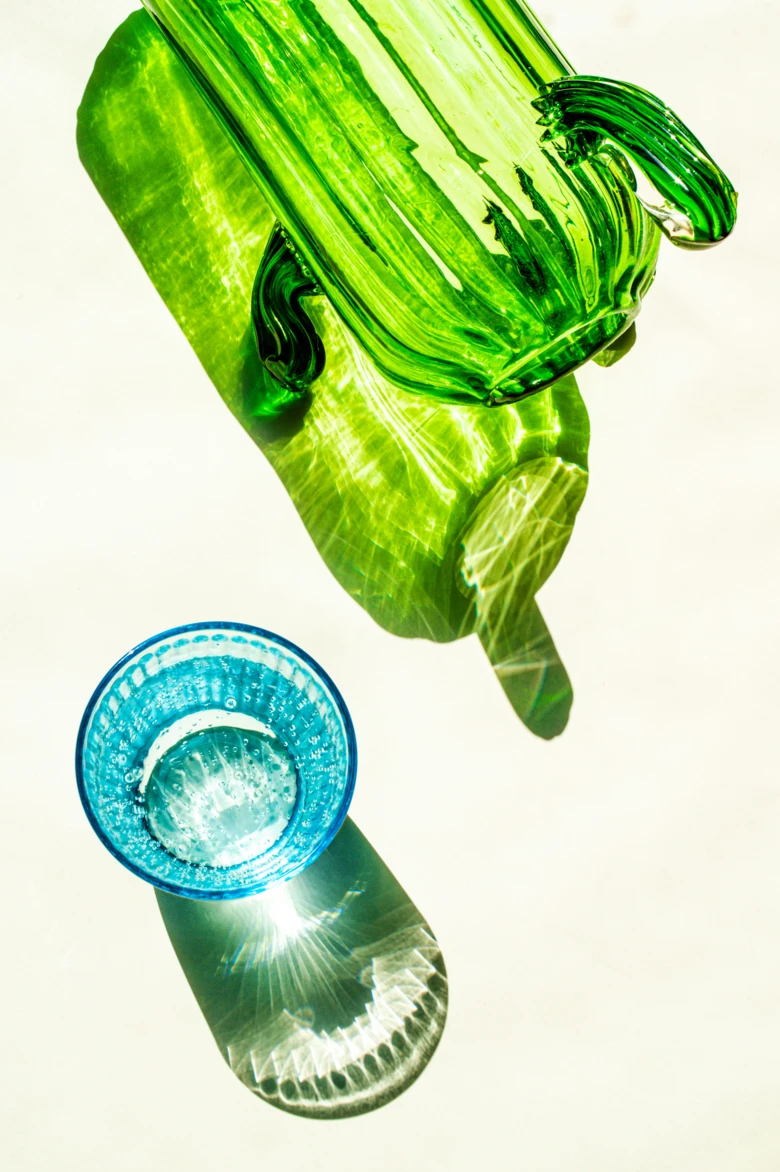 Grüne Glaskaraffe in Kaktusform und ein blaues Glas